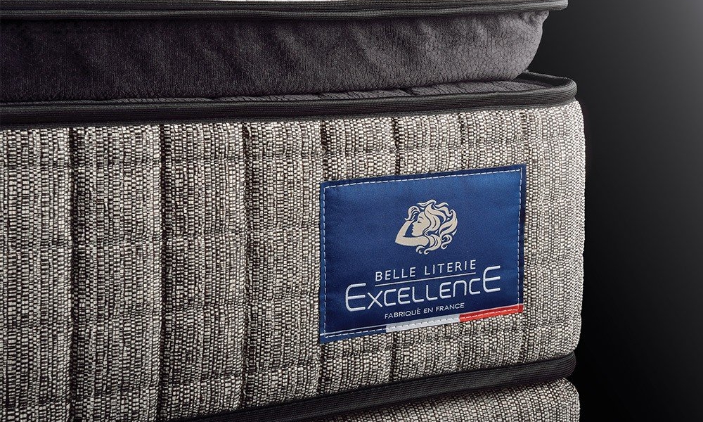 Gros plan d'un matelas Belle Literie Excellence avec un motif texturé et une étiquette bleue sur le côté, mettant en valeur sa qualité inspirée de Paris. Canape Paris by Atelier Bis