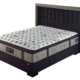 Un matelas au dessus matelassé repose sur un cadre de lit rembourré foncé doté d'une tête de lit haute de style parisien, dégageant un air de qualité. Canape Paris by Atelier Bis