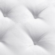 Gros plan d'une surface de matelas capitonnée blanche avec des motifs circulaires texturés sur le tissu, rappelant le design élégant que vous trouveriez dans un Canapé primé chic de Paris. Canape Paris by Atelier Bis