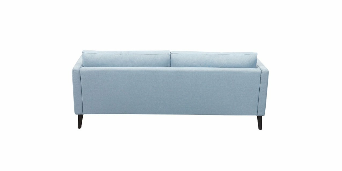 Vue arrière d'un canapé bleu clair aux pieds noirs, présenté dans un showroom parisien sur fond blanc, incarnant la véritable qualité. Canape Paris by Atelier Bis