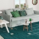 Un salon cosy avec un canapé bleu clair, des coussins à motifs, un tapis vert et des livres empilés dégage un charme parisien. Une table d'appoint blanche complète le look avec une qualité sans effort. Canape Paris by Atelier Bis