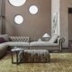 Salon sophistiqué avec un canapé sectionnel taupe, des chaises violettes, des fenêtres rondes et un tapis texturé qui respire la qualité. Canape Paris by Atelier Bis
