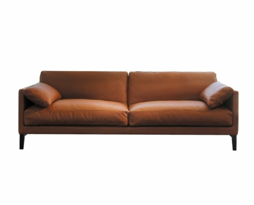 Canapé en cuir marron avec deux coussins, pieds en bois et design minimaliste qui incarne l'élégance de Paris. Équilibrant parfaitement prix et qualité, il se pose gracieusement sur un fond blanc uni. Canape Paris by Atelier Bis
