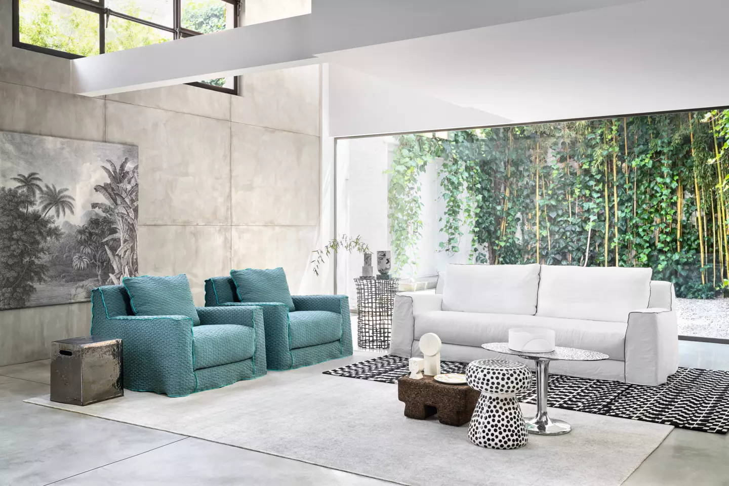 Découvrez un salon moderne rappelant un showroom parisien, avec des fauteuils bleu sarcelle, un canapé blanc immaculé et des œuvres d'art abstraites saisissantes. De grandes fenêtres offrent une vue imprenable sur la verdure luxuriante à l'extérieur, le tout conçu avec une qualité irréprochable. Canape Paris by Atelier Bis