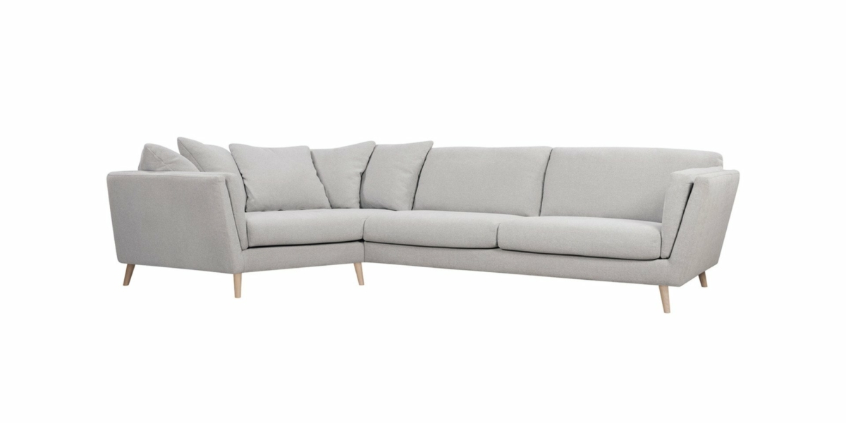 Canapé en L gris clair avec trois coussins d'assise et plusieurs coussins de dossier, le tout posé gracieusement sur des pieds en bois, parfait pour n'importe quelle salle d'exposition. Canape Paris by Atelier Bis