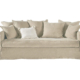 Un canapé beige avec sept coussins assortis et un coussin d'appoint blanc, parfait pour un showroom d'inspiration parisienne. Canape Paris by Atelier Bis