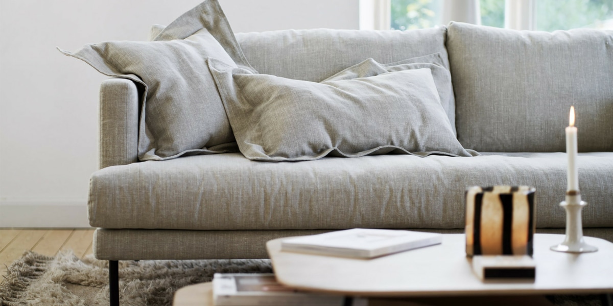 Un espace moderne avec un canapé modulable gris foncé, des meubles laqués blancs et un éclairage LED.