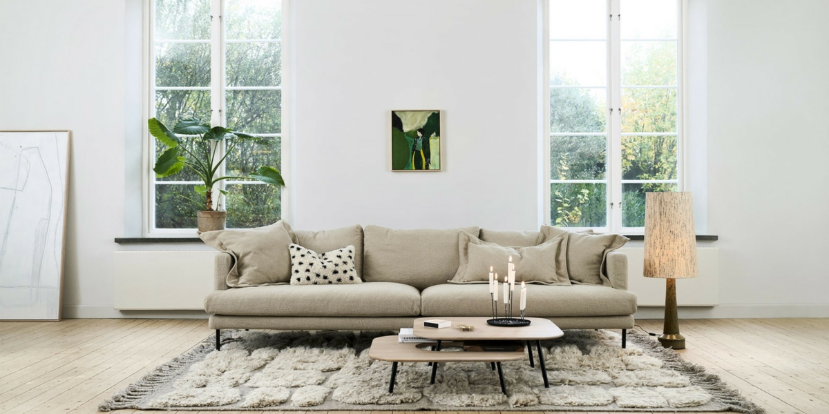 Un salon avec un canapé modulable beige, des coussins colorés et un éclairage chaleureux.