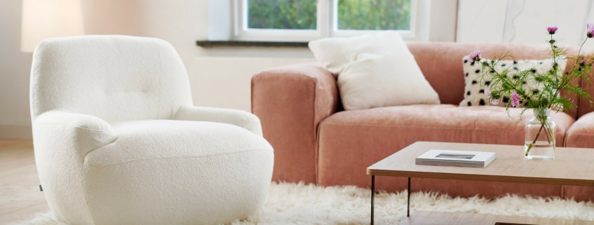 Fauteuil Uma en velours blanc avec un tapis marron et des accents jaunes Le fauteuil en velours blanc repose sur un tapis marron, avec des accents jaunes dispersés dans la pièce pour une touche de gaieté.