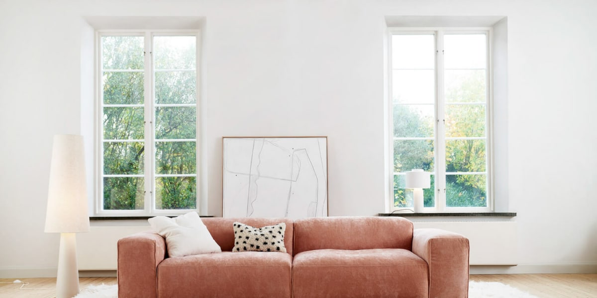 Un salon avec un canapé rose pâle, des coussins colorés et une table basse en métal doré.