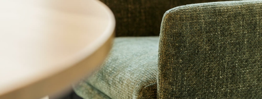 Fauteuil Moa Bistro en cuir brun dans un salon avec des murs en briques apparentes Le fauteuil en cuir brun se trouve dans un salon industriel avec des murs en briques apparentes, créant une ambiance chaleureuse et rustique.