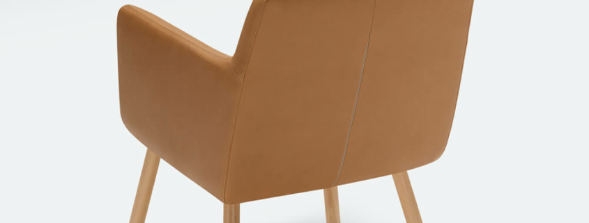 Fauteuil Moa Bistro en tissu jaune moutarde avec une table basse vintage Le fauteuil en tissu jaune moutarde se trouve à côté d'une table basse vintage, ajoutant une touche rétro à la pièce.