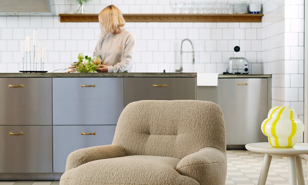 Fauteuil Uma en cuir marron avec une lampe de sol blanche et un vase jaune Le fauteuil en cuir marron est placé à côté d'une lampe de sol blanche et d'un vase jaune, ajoutant une touche moderne et lumineuse à l'espace.