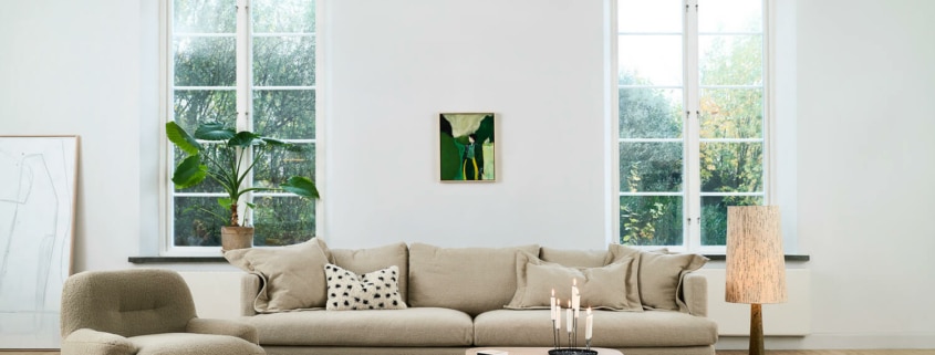 Fauteuil Uma en tissu blanc avec une table d'appoint en bois et une lampe jaune Le fauteuil en tissu blanc est accompagné d'une table d'appoint en bois et d'une lampe jaune, créant une ambiance chaleureuse et accueillante.
