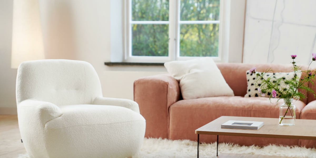 Fauteuil Uma en lin blanc avec des coussins jaunes et marron Le fauteuil en lin blanc est décoré de coussins jaunes et marron, ajoutant des touches de couleur tout en restant élégant.Le fauteuil en tissu jaune moutarde est agrémenté de coussins marron, apportant une touche chaleureuse et accueillante au salon.