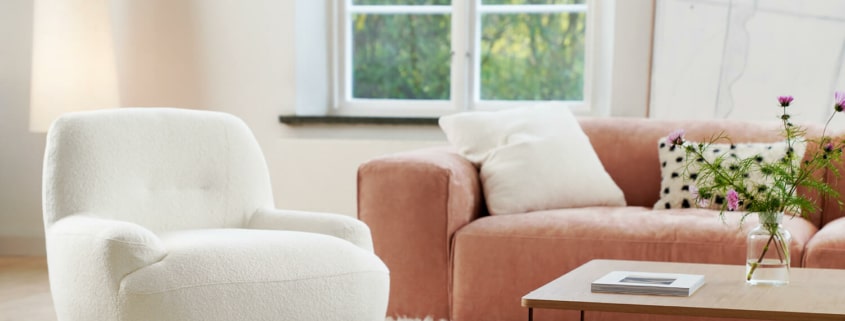 Fauteuil Uma en lin blanc avec des coussins jaunes et marron Le fauteuil en lin blanc est décoré de coussins jaunes et marron, ajoutant des touches de couleur tout en restant élégant.Le fauteuil en tissu jaune moutarde est agrémenté de coussins marron, apportant une touche chaleureuse et accueillante au salon.