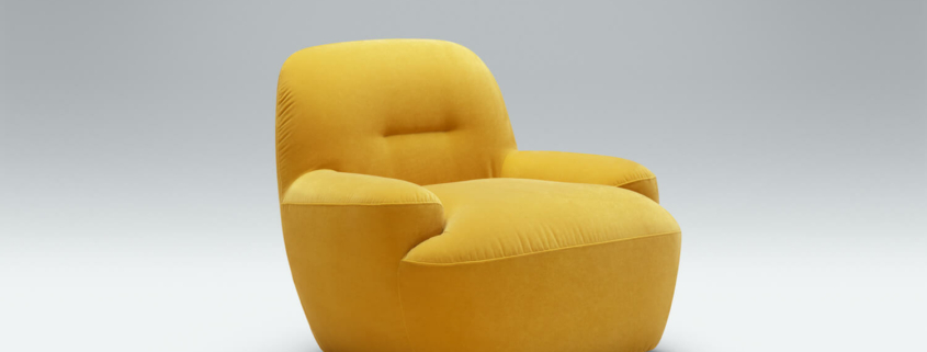 Fauteuil Uma en velours marron avec un plaid jaune Le fauteuil en velours marron est rehaussé par un plaid jaune, parfait pour un coin lecture confortable dans le salon lumineux.