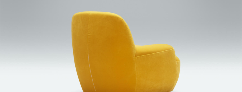 Fauteuil Uma en lin jaune avec une étagère murale blanche et marron Le fauteuil en lin jaune se trouve à côté d'une étagère murale blanche et marron, offrant un espace fonctionnel et esthétique.