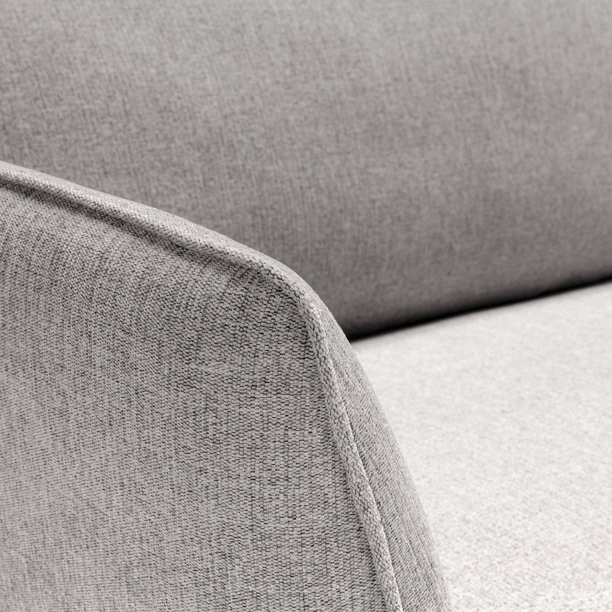 Gros plan d'un accoudoir de canapé en tissu gris, mettant en valeur le revêtement texturé et le design simple et moderne de cet élégant canapé. Canape Paris by Atelier Bis