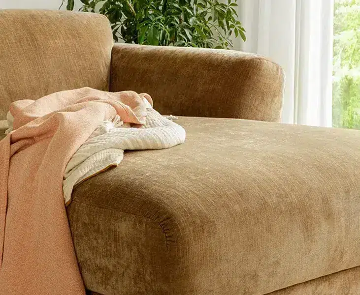 Une photo du canapé Asta marron dans un salon de style scandinave avec des accents de couleur pastel et des meubles en bois clair pour une ambiance douce et épurée.