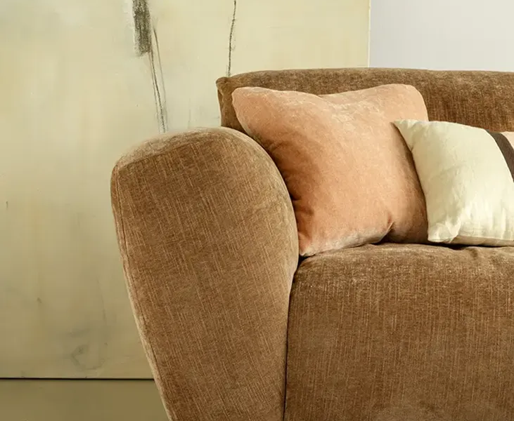 Une image du canapé Asta marron dans un salon de style classique avec des rideaux en velours et des tapis persans pour une atmosphère élégante et intemporelle.