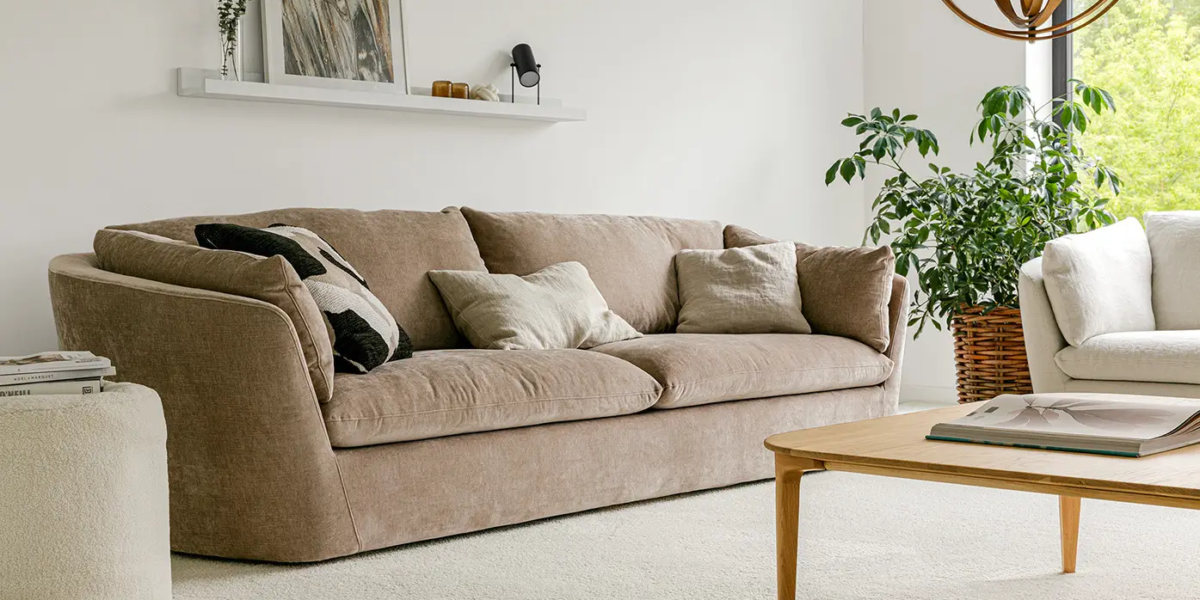 Une photo du canapé Bonnie dans un salon de style rustique avec un tapis en jute et des coussins en lin pour une ambiance chaleureuse et naturelle.