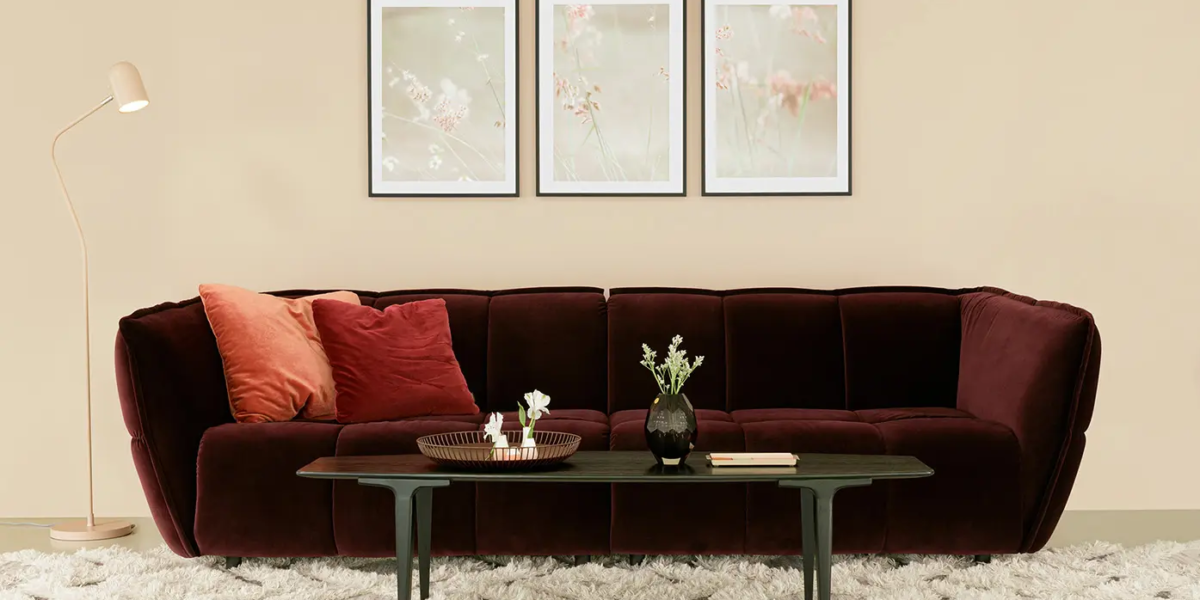 Une photo du canapé rose dans un décor bohème avec des tapis ethniques et des coussins aux motifs floraux pour une ambiance éclectique et chaleureuse.