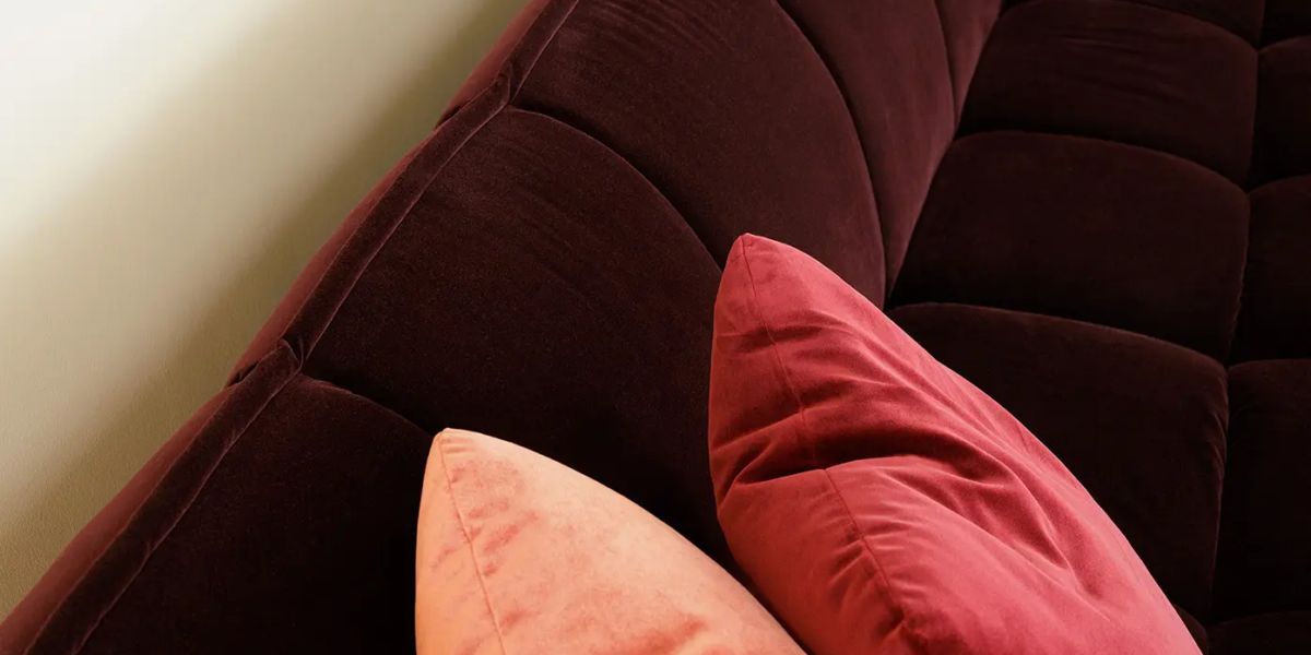 Une photo du canapé rose dans un salon élégant avec des rideaux en velours et des accents dorés pour une ambiance luxueuse et sophistiquée.