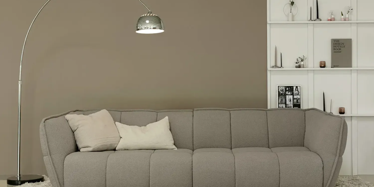 Une image du canapé Clyde gris avec des coussins et une couverture en fausse fourrure pour une ambiance chaleureuse et confortable.