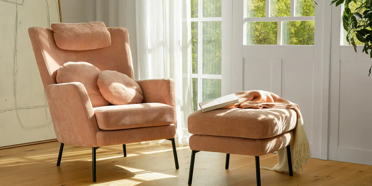 Fauteuil Paris en tissu rose clair avec repose-pieds assorti dans un salon lumineux.