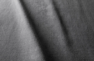 Gros plan sur un tissu gris dont la texture est visible et qui présente des plis verticaux souples. Canape Paris by Atelier Bis