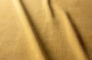 Tissu jaune avec une surface texturée et des plis doux et ondulés qui traversent le tissu en diagonale. Canape Paris by Atelier Bis