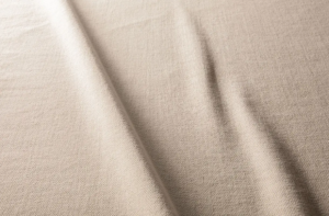 Tissu beige texturé avec des plis subtils et des ombres qui courent en diagonale sur la surface. Canape Paris by Atelier Bis