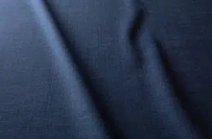 Tissu bleu foncé à la texture douce et aux plis délicats et irréguliers qui courent sur la surface. Canape Paris by Atelier Bis