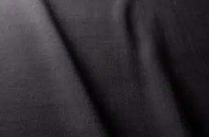 Gros plan sur un tissu texturé gris foncé, aux plis délicats et à l'éclairage doux. Canape Paris by Atelier Bis