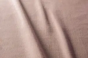 Tissu rose pâle à la texture visible et aux plis doux et délicats qui courent en diagonale sur la surface. Canape Paris by Atelier Bis