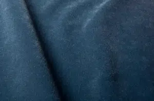 Gros plan d'un tissu de velours bleu à la texture douce et à la brillance subtile, montrant un pli en diagonale. Canape Paris by Atelier Bis