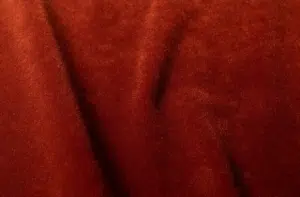 Gros plan sur un tissu de velours rouge doux, aux plis délicats et aux ombres subtiles. Canape Paris by Atelier Bis