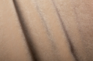 Gros plan sur un tissu de velours brun clair à la texture douce et aux plis délicats. Canape Paris by Atelier Bis