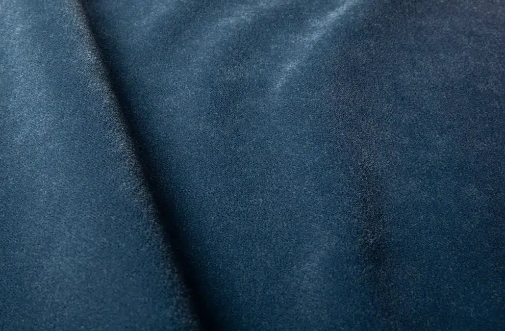 Gros plan sur un tissu en daim bleu foncé, montrant sa texture douce et son éclat subtil. Canape Paris by Atelier Bis