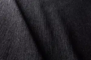Gros plan d'un tissu denim foncé avec une texture de tissage visible et des ombres diagonales douces sur la surface. Canape Paris by Atelier Bis