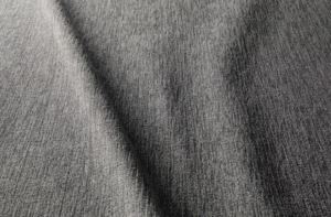 Gros plan sur un tissu gris texturé dont la trame est visible et dont le pli diagonal crée une ombre. Canape Paris by Atelier Bis