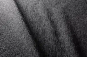 Gros plan d'un tissu texturé gris foncé avec un motif de tissage visible et une ombre diagonale subtile. Canape Paris by Atelier Bis