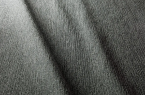 Gros plan d'un tissu gris texturé avec des crêtes visibles et des ombres diagonales. Canape Paris by Atelier Bis