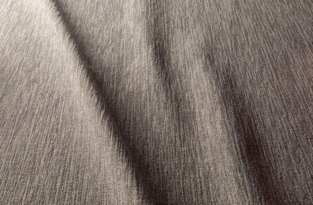 Tissu texturé gris avec des plis diagonaux et des ombres subtiles créant une apparence douce et ondulée. Canape Paris by Atelier Bis