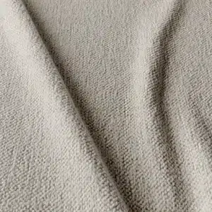 Gros plan d'un tissu texturé beige clair avec des plis visibles et une surface tissée légèrement rugueuse. Canape Paris by Atelier Bis