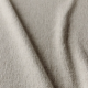 Gros plan sur un tissu beige texturé, à la surface douce et bosselée et aux plis délicats. Canape Paris by Atelier Bis