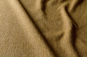 Gros plan sur un tissu texturé jaune moutarde aux plis souples et au motif de tissage visible. Canape Paris by Atelier Bis