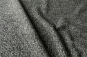 Gros plan sur un tissu gris texturé aux plis souples et au motif tissé visible. Canape Paris by Atelier Bis
