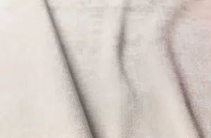 Gros plan sur un tissu texturé beige clair aux plis souples et au motif de tissage visible. Canape Paris by Atelier Bis